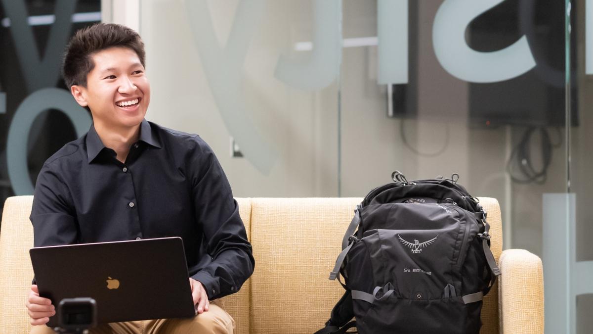 Simon Nguy holds a laptop while seated in the student level of the J.A. Albertson Building.